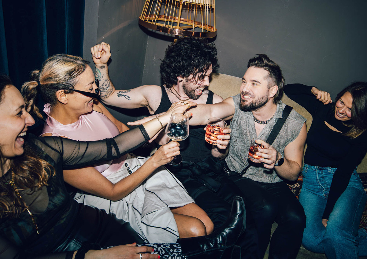 Freunde feiern gemeinsam mit Cocktails in der Bar des KINK Berlin – entspannter Abend mit Drinks